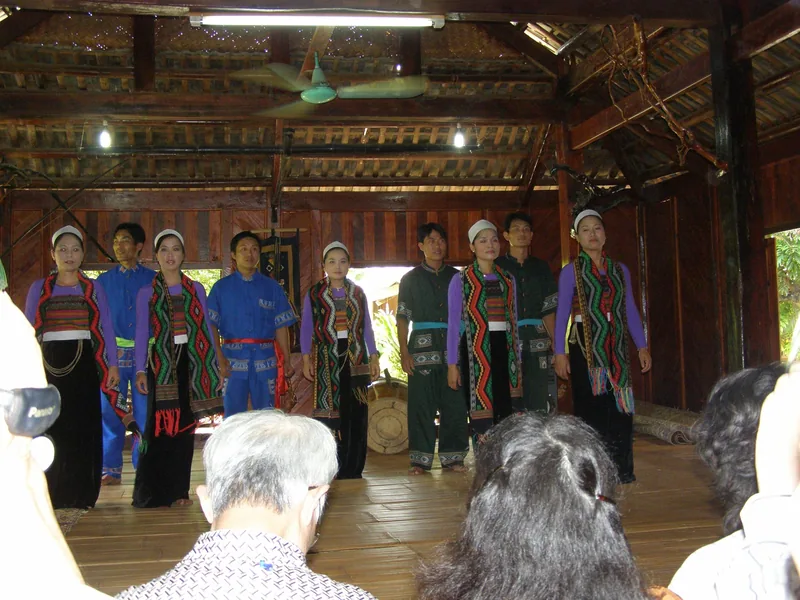Performers in traditional ethnic costumes sing for visitors inside a wooden stilt house in Mai Chau.